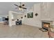 Open living room with neutral tile floors, fan, fireplace, and space for a work area at 5990 Ablette Ave, Las Vegas, NV 89122