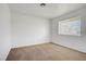 Simple bedroom with carpet, a window, and plain white walls, providing a blank canvas for customization at 6727 E Washington Ave, Las Vegas, NV 89110
