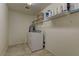 Well-lit laundry room with tile flooring, washer, dryer, and shelving for storage at 7104 Flathead River Ave, Las Vegas, NV 89179