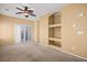 Open living room featuring neutral paint and carpet, ceiling fan, built-in shelves, and a sliding door to the balcony at 728 Hardy Way # E, Mesquite, NV 89027