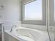 Bright bathroom features a large soaking tub under a frosted window at 7753 Petite Pillar Ct, Las Vegas, NV 89149