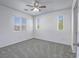 Bright bedroom featuring neutral carpet, ceiling fan, and three bright windows at 7753 Petite Pillar Ct, Las Vegas, NV 89149