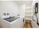 Well-lit laundry room featuring a washer, dryer, and shelving for storage at 831 E Valiant Ave, Pahrump, NV 89060