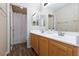 Bathroom featuring a double sink vanity with wood cabinets, large mirror, and shower/tub with white curtain at 9039 Alex Creek Ave, Las Vegas, NV 89149