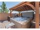 Hot tub bubbling under wooden pergola with string lights, barbecue and brick patio at 9690 Langden Brook St, Las Vegas, NV 89178