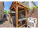 Wooden backyard pergola with barbecue grill, bar, mini-fridge and stacked outdoor chairs at 9690 Langden Brook St, Las Vegas, NV 89178