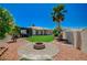 View of the backyard showcasing a brick fire pit, artificial grass, desert landscaping, and covered patio at 983 Cutter St, Henderson, NV 89011
