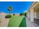 Spacious backyard featuring artificial grass, desert landscaping, covered patio, and palm trees at 983 Cutter St, Henderson, NV 89011