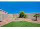 Landscaped backyard featuring a circular brick fire pit, artificial grass, desert landscaping, and block wall at 983 Cutter St, Henderson, NV 89011