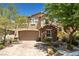 Inviting two-story home with brick driveway, two-car garage, stone facade, and mature landscaping at 10474 Palmadora St, Las Vegas, NV 89178