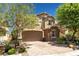 Charming two-story home with a brick driveway, stone accents, a two-car garage, and lush landscaping at 10474 Palmadora St, Las Vegas, NV 89178