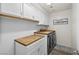 Efficient laundry room with butcher block countertops, white cabinetry, and modern washer/dryer at 10474 Palmadora St, Las Vegas, NV 89178