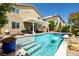 Backyard oasis featuring a sparkling blue swimming pool with waterfall feature, hot tub and lounge area at 10474 Palmadora St, Las Vegas, NV 89178