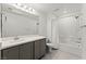 A bathroom featuring a shower-tub combo, toilet, and a sink with a gray cabinet at 1103 Tektite Ave, Henderson, NV 89011