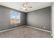 A well-lit, empty bedroom featuring neutral carpet, gray walls, ceiling fan, and a bright window at 1103 Tektite Ave, Henderson, NV 89011