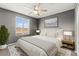 A modern bedroom featuring neutral carpet, gray walls, ceiling fan, and a bright window at 1103 Tektite Ave, Henderson, NV 89011