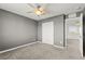 A bedroom featuring neutral carpeting, walls, and a ceiling fan and a closet with white doors at 1103 Tektite Ave, Henderson, NV 89011