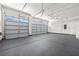 A well-lit, spacious three car garage with gray epoxy flooring, overhead storage racks and white walls at 2164 Noonday Ct, Henderson, NV 89052
