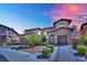 Elegant two-story home with a three-car garage, accented by stone details and landscaped garden at dusk at 362 Port Reggio St, Las Vegas, NV 89138