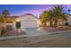 Attractive home exterior with a two-car garage, gravel landscaping, and mature palm trees at 433 Old Palms Dr, Las Vegas, NV 89123
