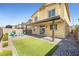 Inviting backyard with artificial turf, a covered patio with lights, and a cozy fire pit seating area for outdoor enjoyment at 4519 Stardusk Falls Ave, North Las Vegas, NV 89084