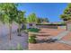 Gravel backyard with mature trees and landscaping features a storage building at 5725 N Durango Dr, Las Vegas, NV 89149