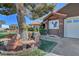 Charming home exterior with mature tree, stone bench, and well-manicured landscaping at 5725 N Durango Dr, Las Vegas, NV 89149