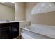 Bathroom featuring marble-surround soaking tub, half-round window, and custom vanity at 6403 Brandon Hills Ct, Las Vegas, NV 89139