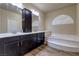 Bathroom features a dual vanity, a soaking tub with marble surround, and wood-look tile flooring at 6403 Brandon Hills Ct, Las Vegas, NV 89139