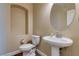 Powder room includes pedestal sink, circular mirror, and water closet with niche at 6403 Brandon Hills Ct, Las Vegas, NV 89139