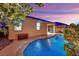 Backyard with a pool, covered patio, and manicured trees at dusk at 708 Kibbey St, Las Vegas, NV 89178