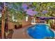 Backyard with a pool, covered patio, and manicured trees at dusk at 708 Kibbey St, Las Vegas, NV 89178