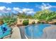 A kidney-shaped pool is surrounded by lush landscaping and cozy seating on a sunny day at 708 Kibbey St, Las Vegas, NV 89178
