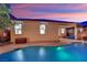 Backyard with a pool, covered patio, and manicured trees at dusk at 708 Kibbey St, Las Vegas, NV 89178