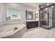 A luxurious bathroom with a marble floor, soaking tub under a window, and a modern glass shower stall at 722 Descartes Ave, Henderson, NV 89002