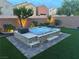 Inviting backyard hot tub features a stone surround, ambient lighting, and lush artificial turf at 7424 Rainford St, Las Vegas, NV 89148