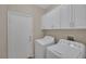 Convenient laundry room featuring a washing machine and dryer with overhead cabinets at 7544 Coral River Dr, Las Vegas, NV 89131