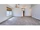 Spacious living room with grey carpet, a ceiling fan, and natural light from the window at 8309 Windrush Ave, Las Vegas, NV 89117