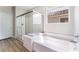 Bright bathroom with a glass enclosed shower and separate tub with a window at 8351 Vinamala Ave, Las Vegas, NV 89149