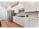 White kitchen featuring stainless steel appliances, ample counter space, and wood-look flooring at 8351 Vinamala Ave, Las Vegas, NV 89149