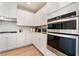 Contemporary kitchen with white cabinetry, stainless steel oven, and natural wood flooring at 8351 Vinamala Ave, Las Vegas, NV 89149