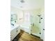 Bright bathroom featuring wood-look floors, a vanity, a tub, and a shower with glass doors at 8616 Willow Cabin St, Las Vegas, NV 89131