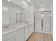 Bathroom featuring double sinks, quartz counters, wood-look tile flooring, and a glass-enclosed shower at 8852 Flora Run Ave, Las Vegas, NV 89166