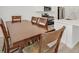 Modern dining room with a large wooden table, hardwood floors, and a view of the well-lit kitchen at 8852 Flora Run Ave, Las Vegas, NV 89166