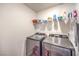 Modern laundry room featuring a front-load washer and dryer with convenient shelving at 9114 Riverlands Ranch St, Las Vegas, NV 89139