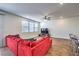 Bright living room featuring a red sofa, wood-style flooring, a ceiling fan, and large windows for natural light at 9114 Riverlands Ranch St, Las Vegas, NV 89139