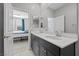 Dual sink bathroom with quartz countertops, dark cabinets, large mirror, and hallway at 10431 Seelos St, Las Vegas, NV 89178