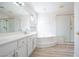 Bright bathroom with a large tub, glass shower, double sinks, and wood-look flooring at 10902 Pentland Downs St, Las Vegas, NV 89141