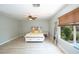 Bright bedroom featuring a ceiling fan, neutral walls, wood-look flooring, and a large window at 10902 Pentland Downs St, Las Vegas, NV 89141