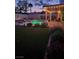 Backyard at dusk, featuring a lit pool, covered patio, and manicured landscaping at 1413 Gentle Brook St, North Las Vegas, NV 89084